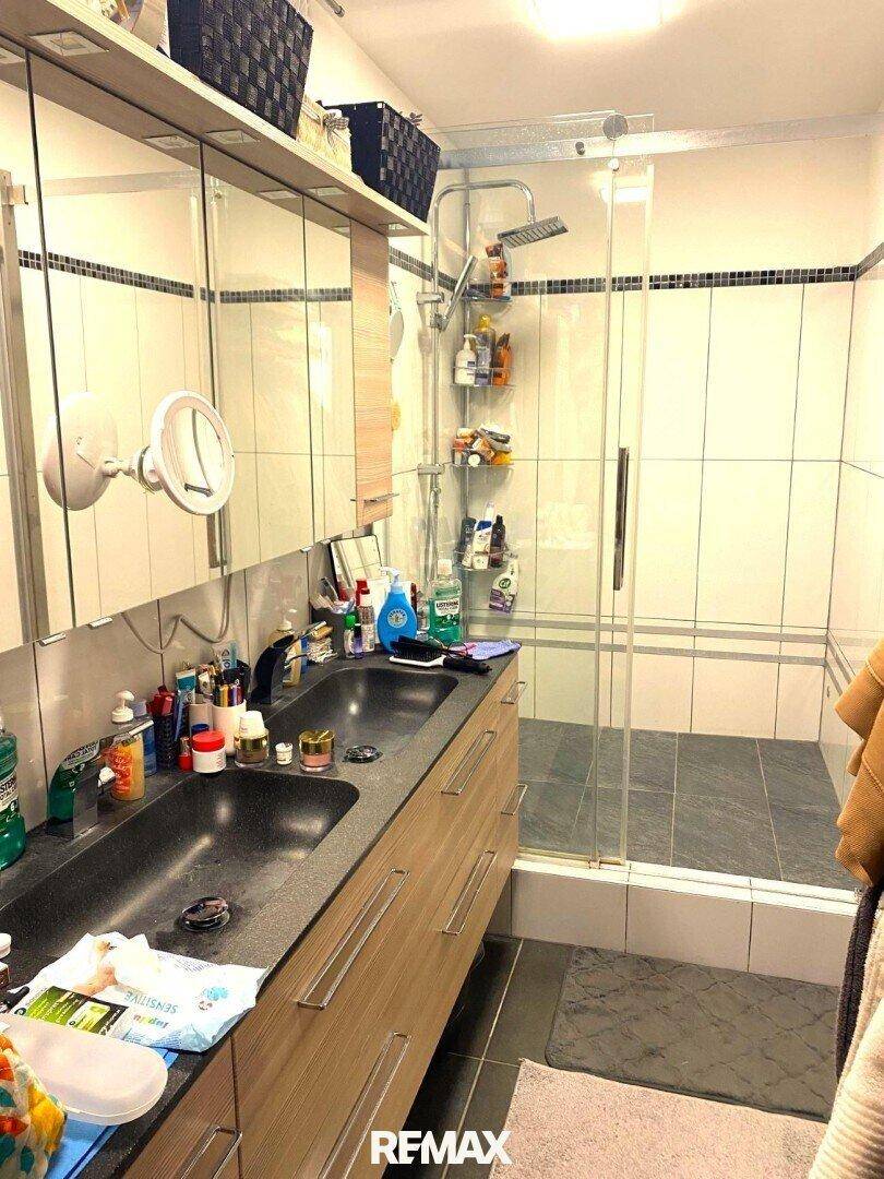 Modernes Badezimmer mit großer begehbarer Dusche, Doppelwaschbecken und Spiegelschrank.