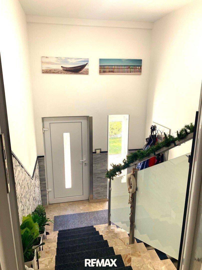 Treppenhaus mit moderner Glasbrüstung und gefliesten Stufen, führt zu den oberen Etagen.