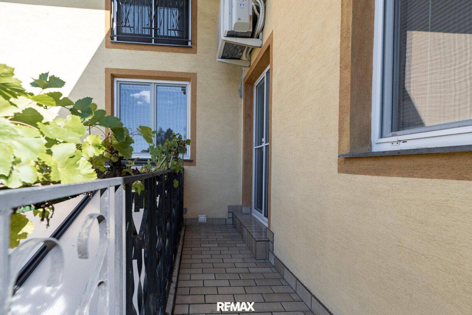 Schmaler Balkon mit Fliesenboden und schmiedeeisernem Geländer.