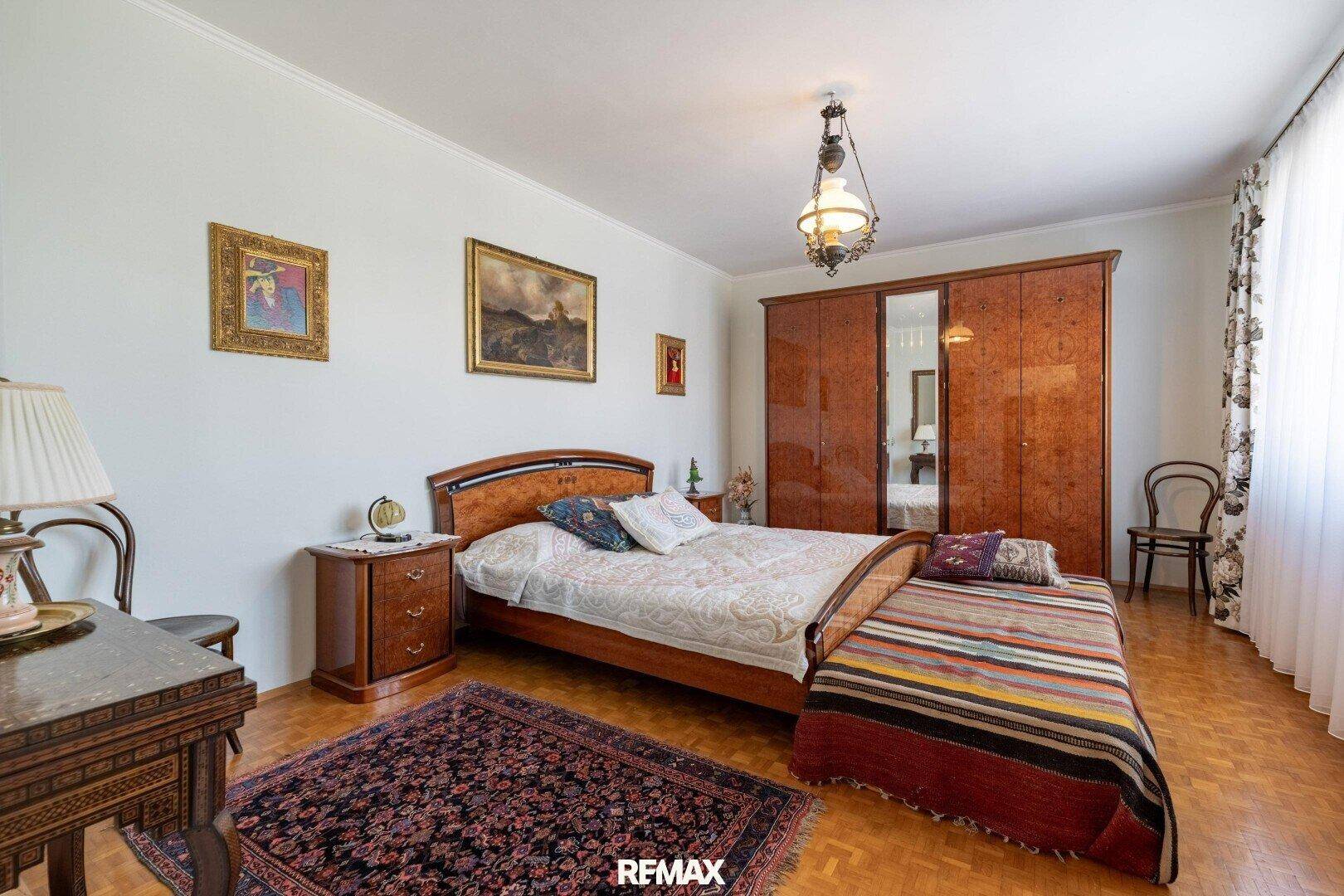 Geräumiges Schlafzimmer mit Doppelbett, Holzschrank und Parkettboden.
