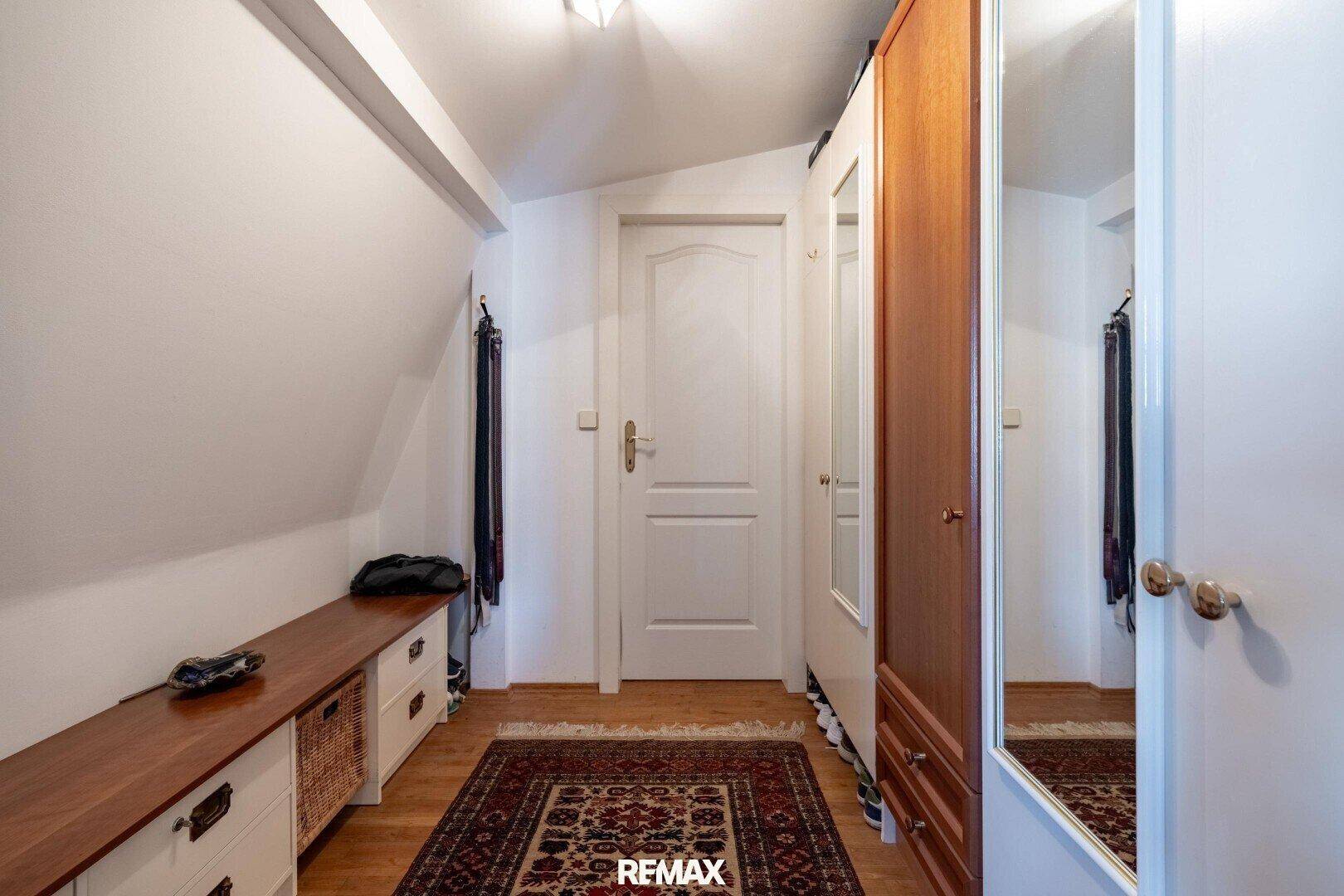Heller Flur mit Kleiderschrank, Sitzbank und Dachschrägen, ideal als Ankleidebereich.