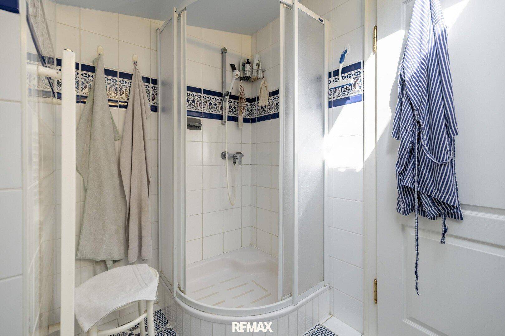 Duschkabine in einem Badezimmer mit weißen und blauen Fliesen, funktional und hell.