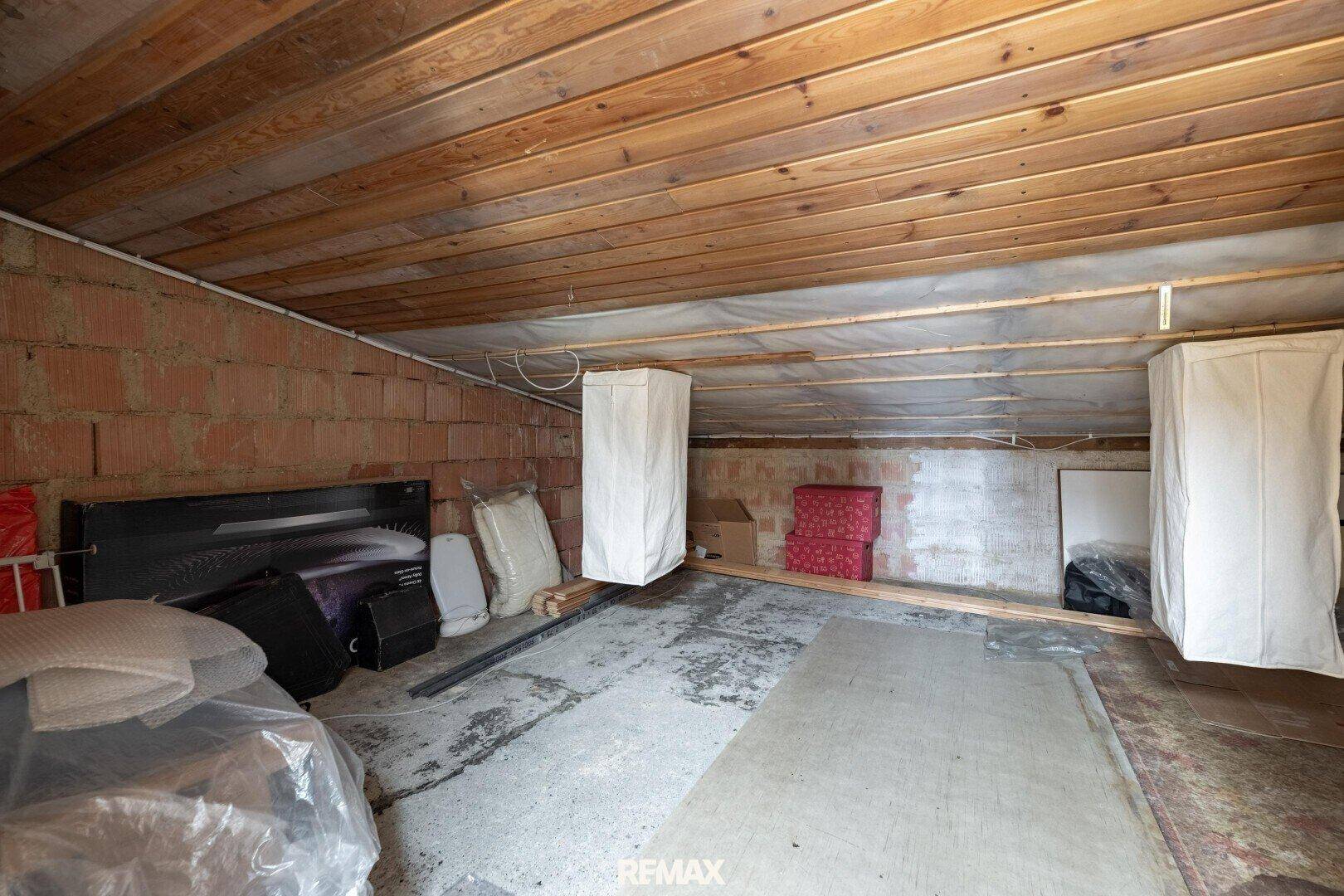 Kellerraum mit Ziegelwänden, Betonboden und Holzdecke, ideal als Lagerfläche.