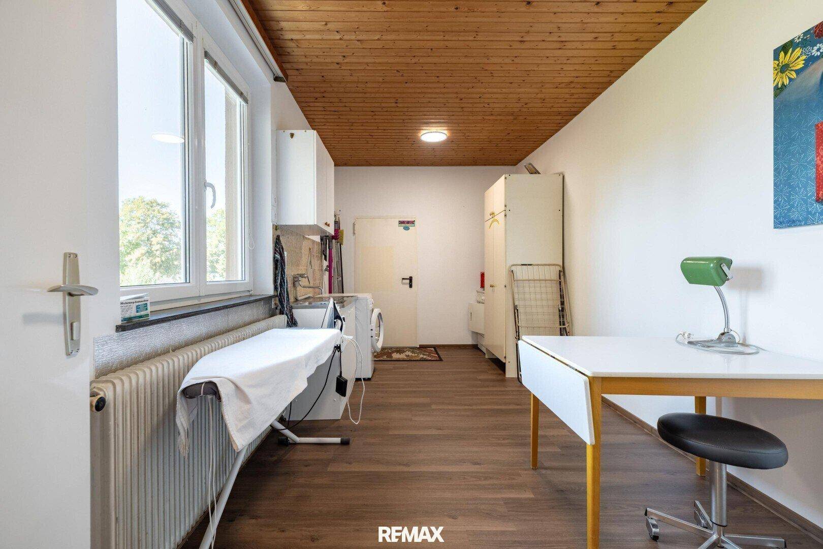 Praktischer Hauswirtschaftsraum mit Waschmaschine, Bügelbrett und Arbeitsbereich.