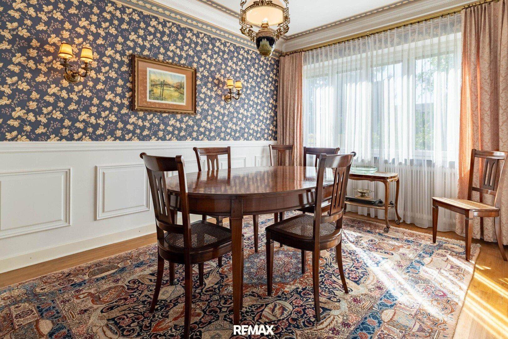 Klassisches Esszimmer mit floraler Tapete, Holztisch und Stühlen für gesellige Runden.