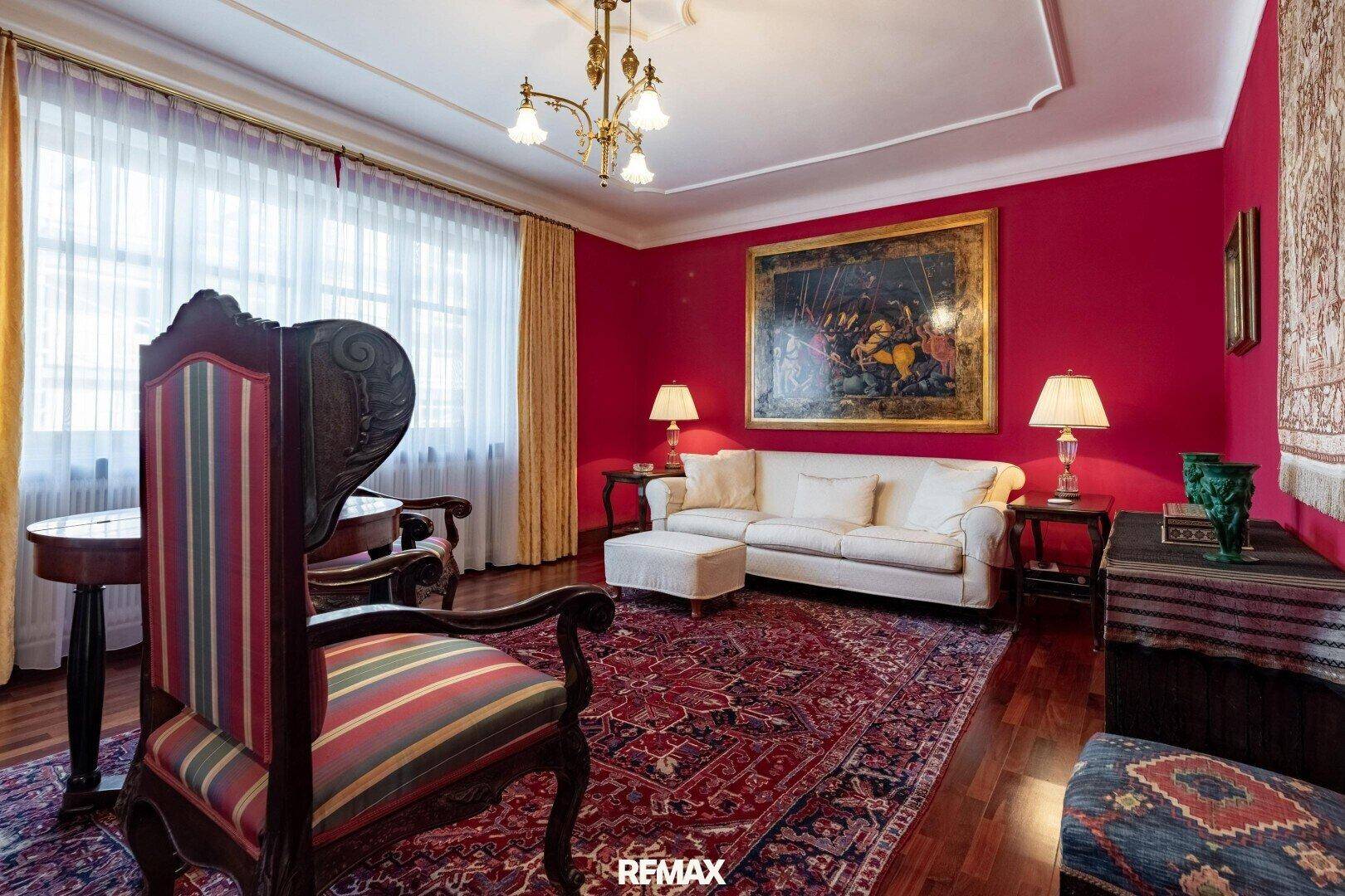 Elegantes Wohnzimmer mit roten Wänden, klassischem Teppich und bequemen Sofas.