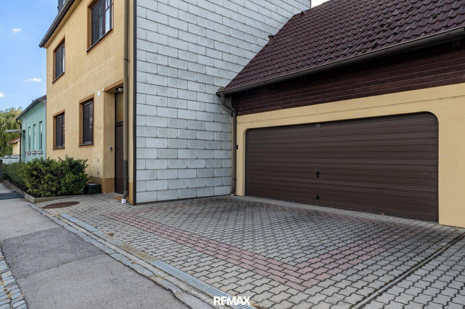 Außenansicht des Hauses mit gepflasterter Einfahrt und integrierter Garage.