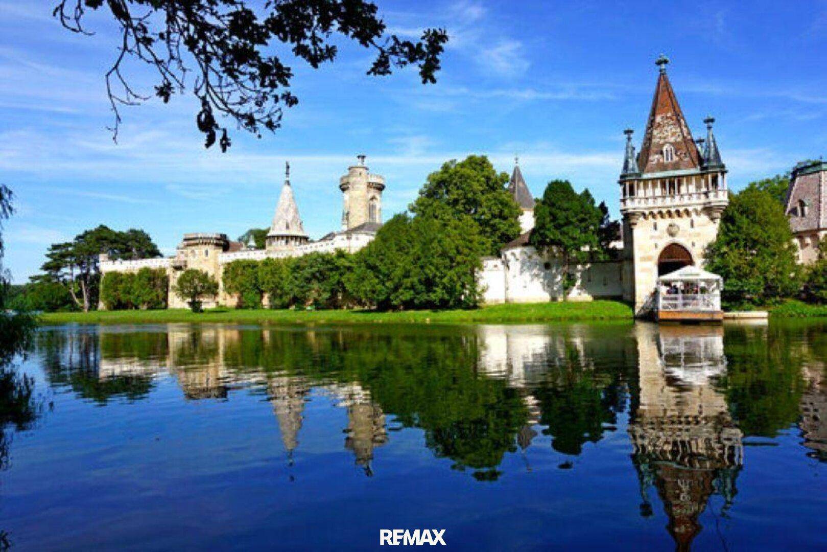 Malerisches Schlossgebäude am Seeufer mit beeindruckender Architektur und Spiegelung im Wasser.