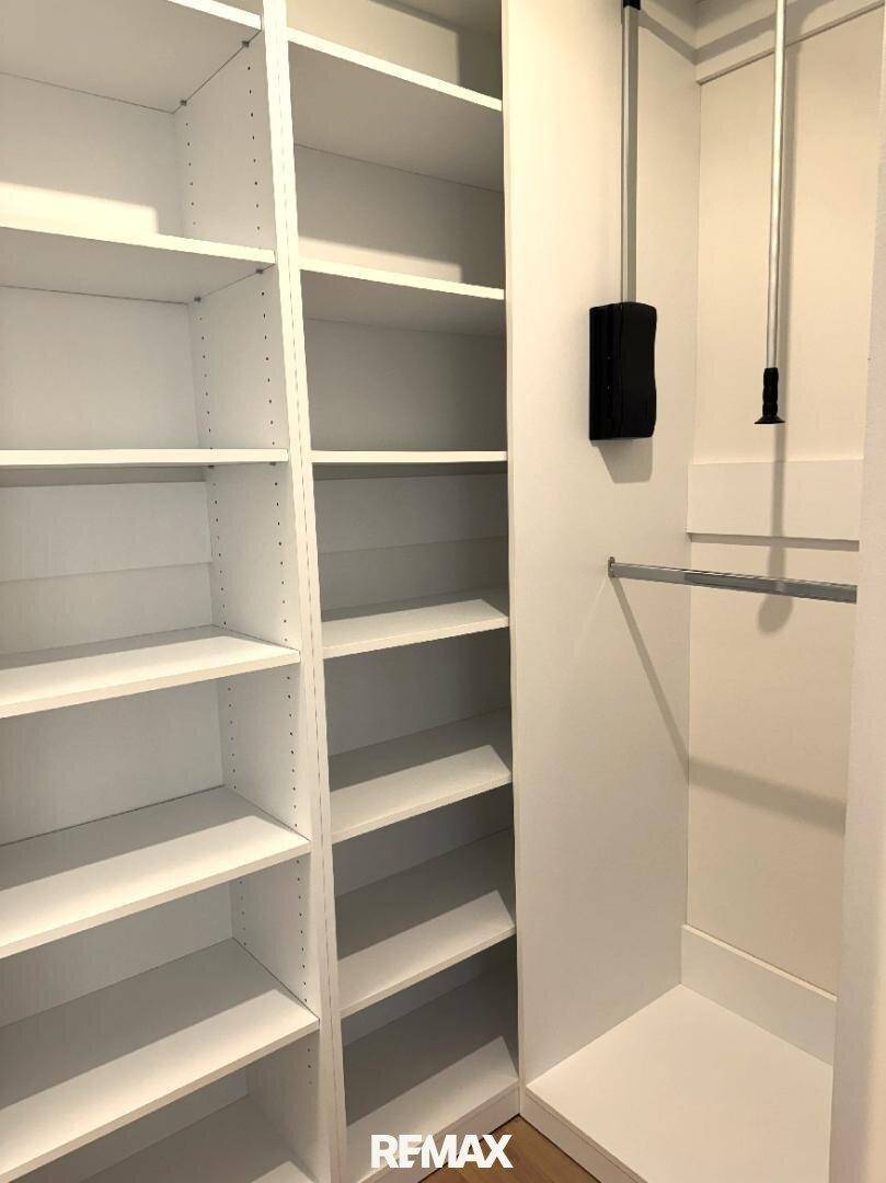 Geräumiger begehbarer Kleiderschrank mit vielen weißen Regalen und Kleiderstangen für optimale Organisation.