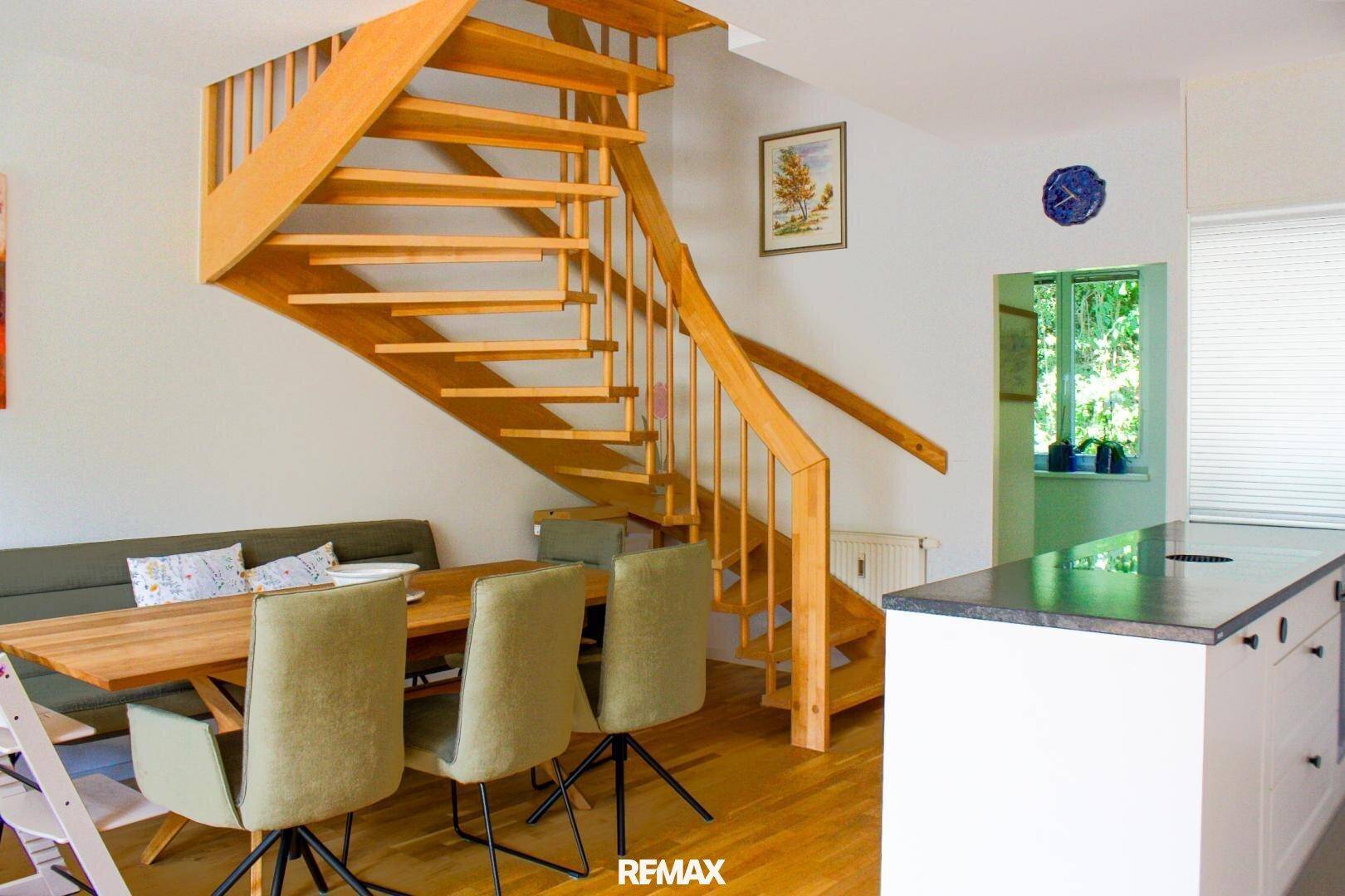 Heller Essbereich mit Holztisch und Stühlen, direkt neben einer offenen Holztreppe gelegen.
