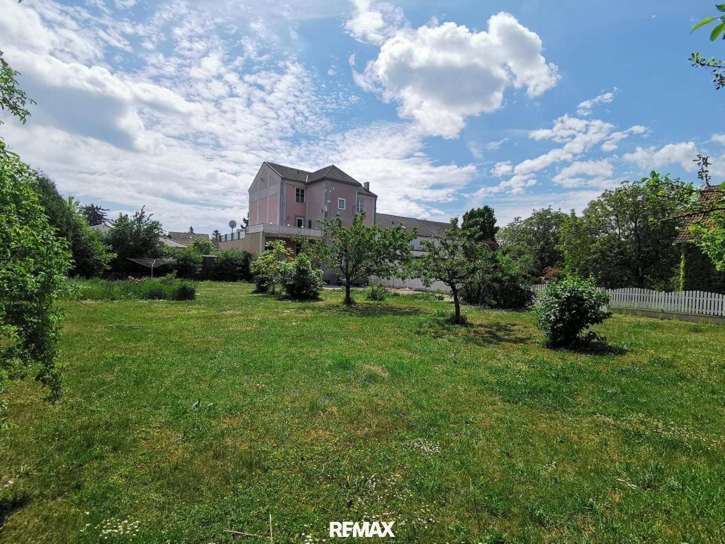 Großer, gepflegter Garten mit Rasenfläche und Obstbäumen vor dem Wohnhaus.