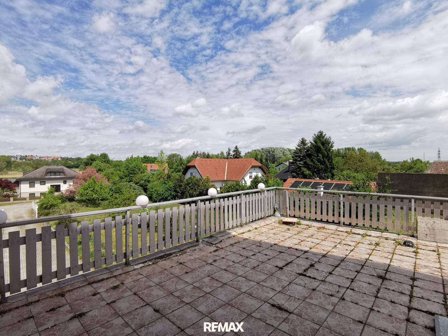 Große Dachterrasse mit Fliesenboden und weitem Blick über die grüne Umgebung.