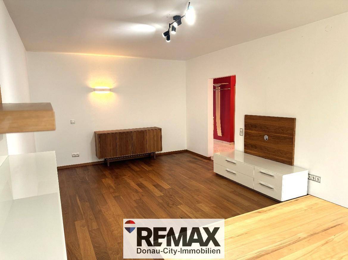 Geräumiges Wohnzimmer mit elegantem Holzfußboden und moderner Einrichtung.
