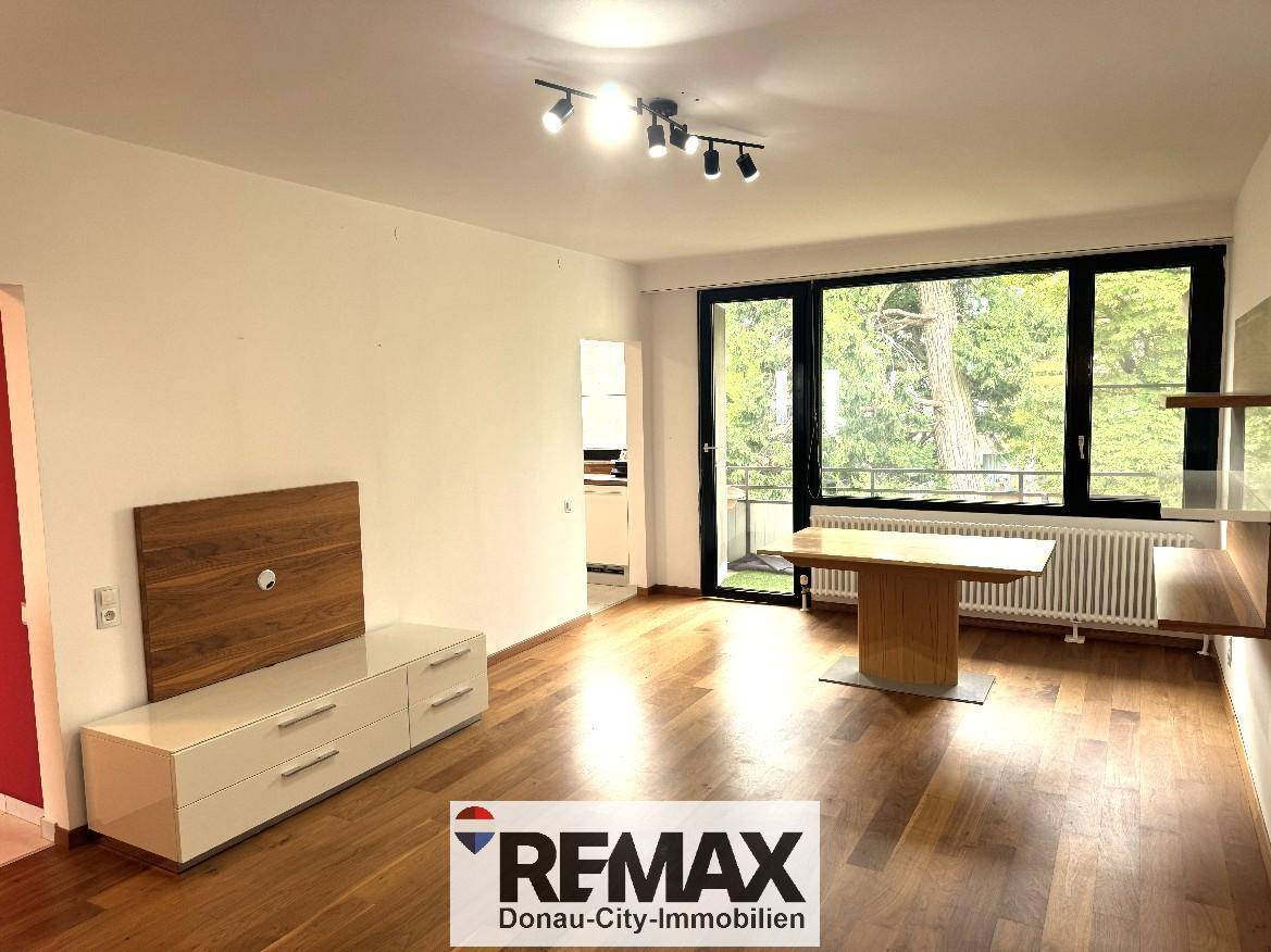Helles Wohnzimmer mit Holzfußboden, großen Fenstern und Blick ins Grüne.