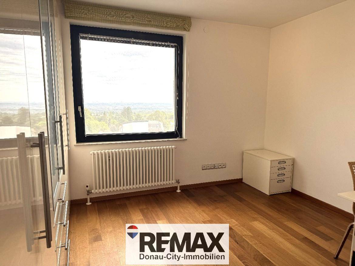 Heller Raum mit Holzfußboden, großem Fenster und einem Heizkörper, ideal als Büro.
