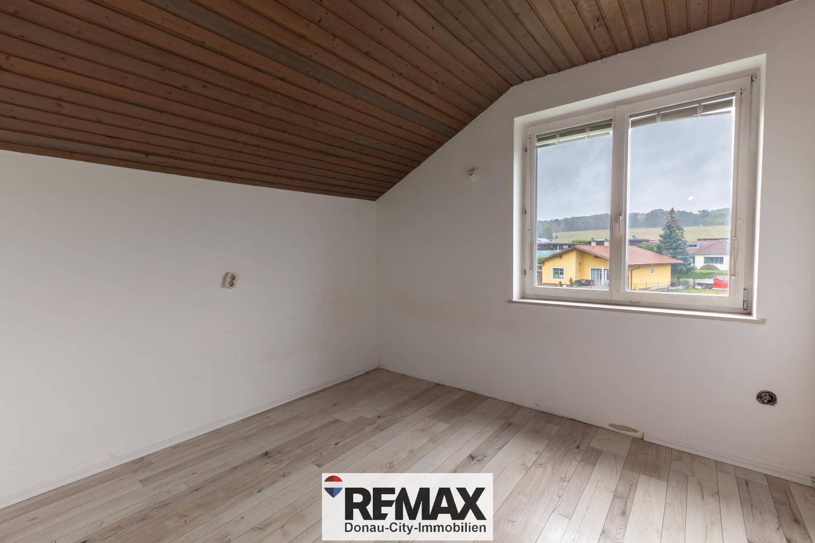 Geräumiges Zimmer im Dachgeschoss mit Holzboden, Dachschräge und weitem Ausblick.