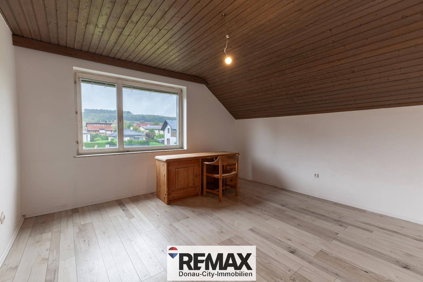 Helles Arbeitszimmer im Dachgeschoss mit Holzboden, Schreibtisch und Ausblick.