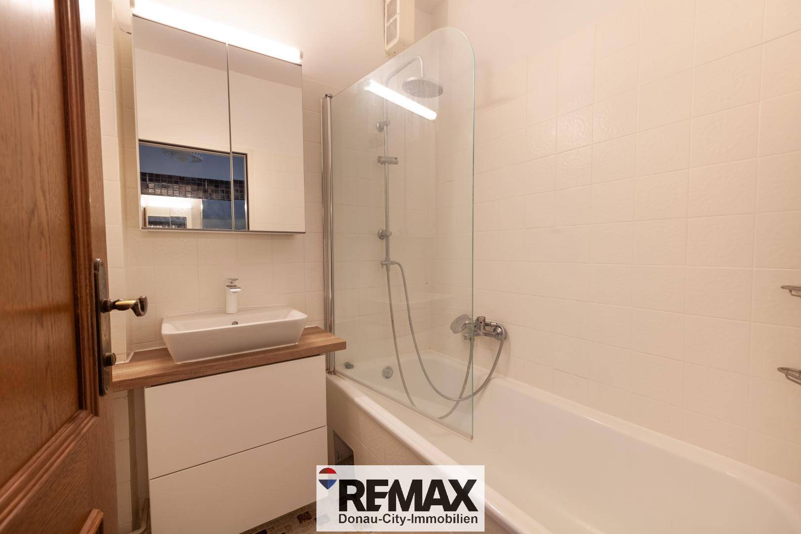 Modernisiertes Badezimmer mit Badewanne, Duschabtrennung und Einzelwaschbecken.