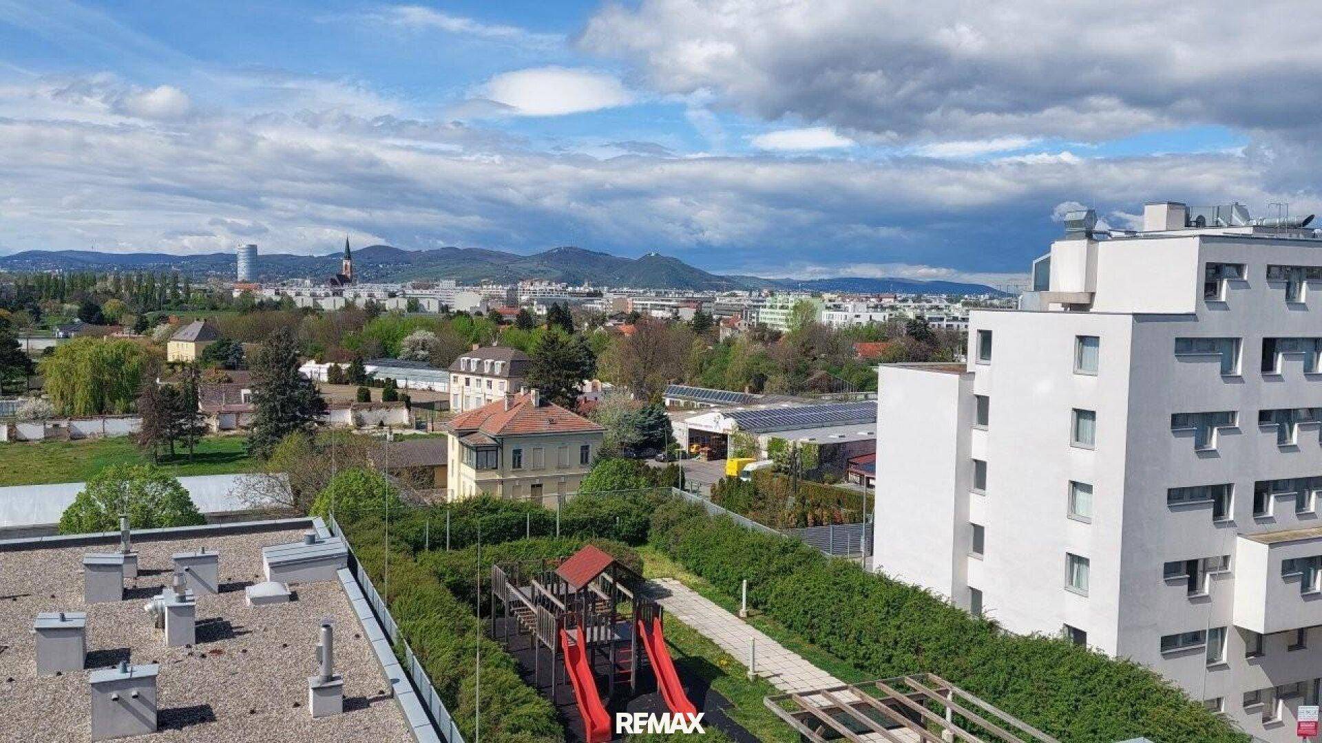 Blick auf einen Gemeinschaftsspielplatz mit Rutschen und Grünflächen zwischen Wohngebäuden.
