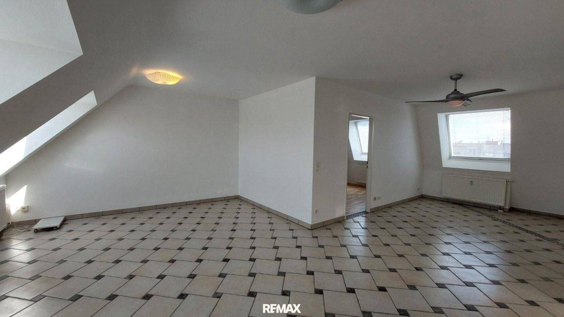 Geräumiges Wohnzimmer mit gemusterten Fliesen, Dachschrägen und Deckenventilator.