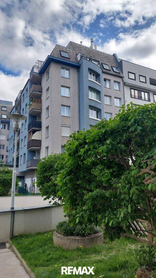 Mehrstöckiges Wohngebäude mit blauen und grauen Fassadenelementen und Dachfenstern.