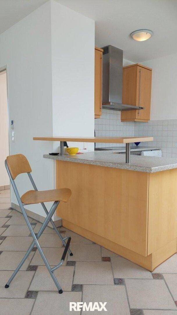 Küchenbereich mit Frühstücksbar, Holzschränken und Dunstabzugshaube, ideal für schnelle Mahlzeiten.