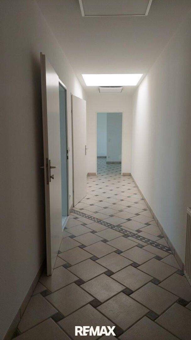 Langer Flur mit gemusterten Fliesen und Oberlicht, der zu weiteren Räumen führt.