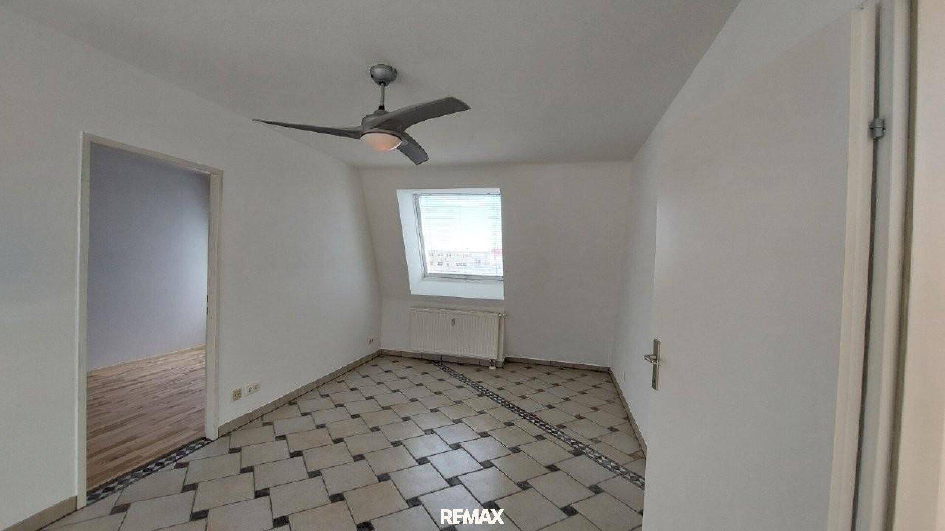 Schlafzimmer mit Fliesenboden, Dachschräge und Deckenventilator, bereit zur Einrichtung.