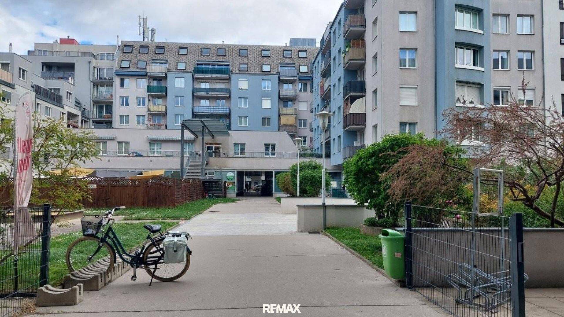 Außenansicht eines Wohnkomplexes mit Fahrradständern und Grünflächen im Vordergrund.