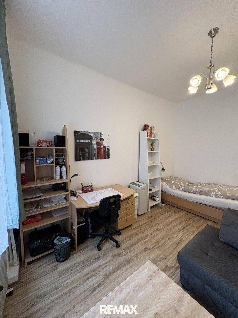 Wohnraum mit Schreibtisch, Regal und Schlafbereich.