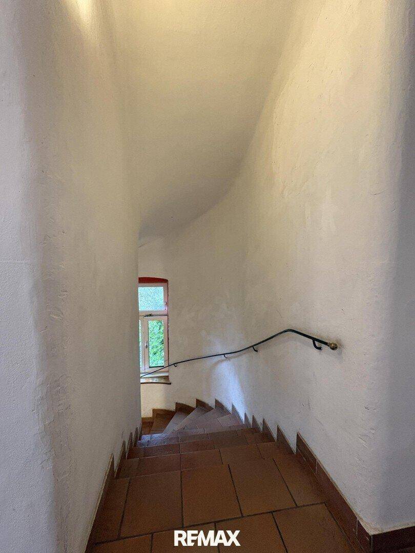 Treppenhaus mit Terrakottafliesen und schlichtem Handlauf.