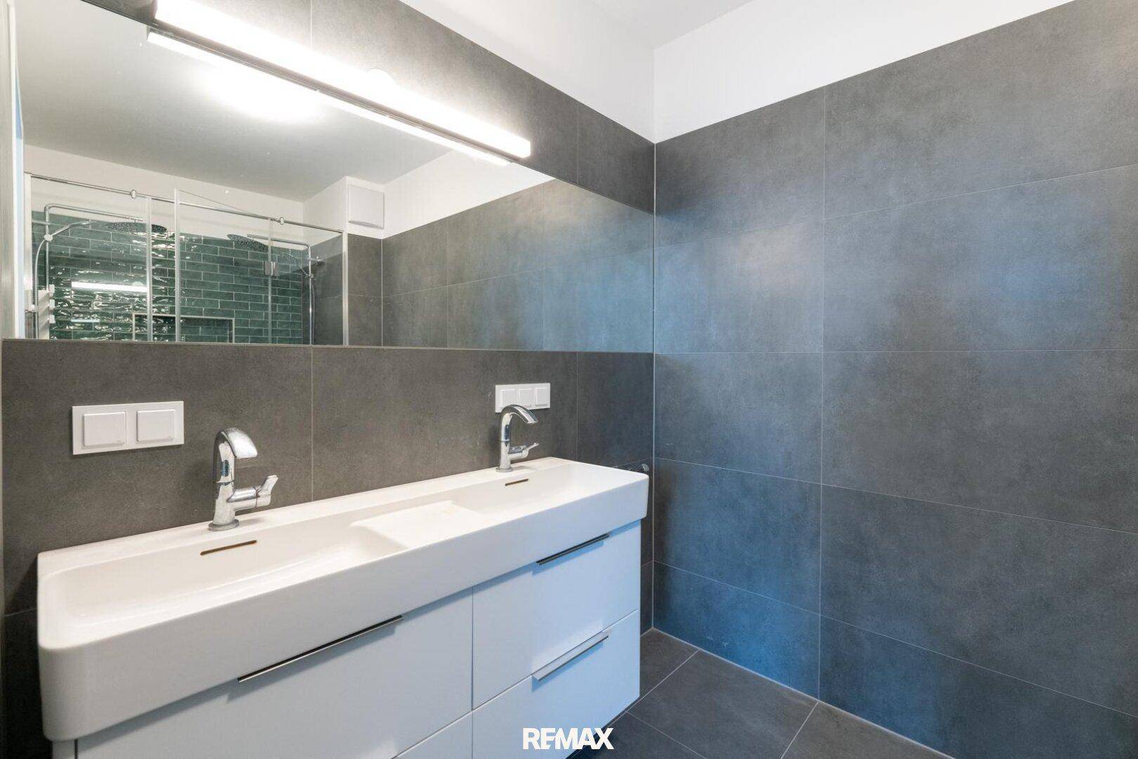 Elegantes Badezimmer mit Doppelwaschbecken, großem Spiegel und modernen Armaturen.