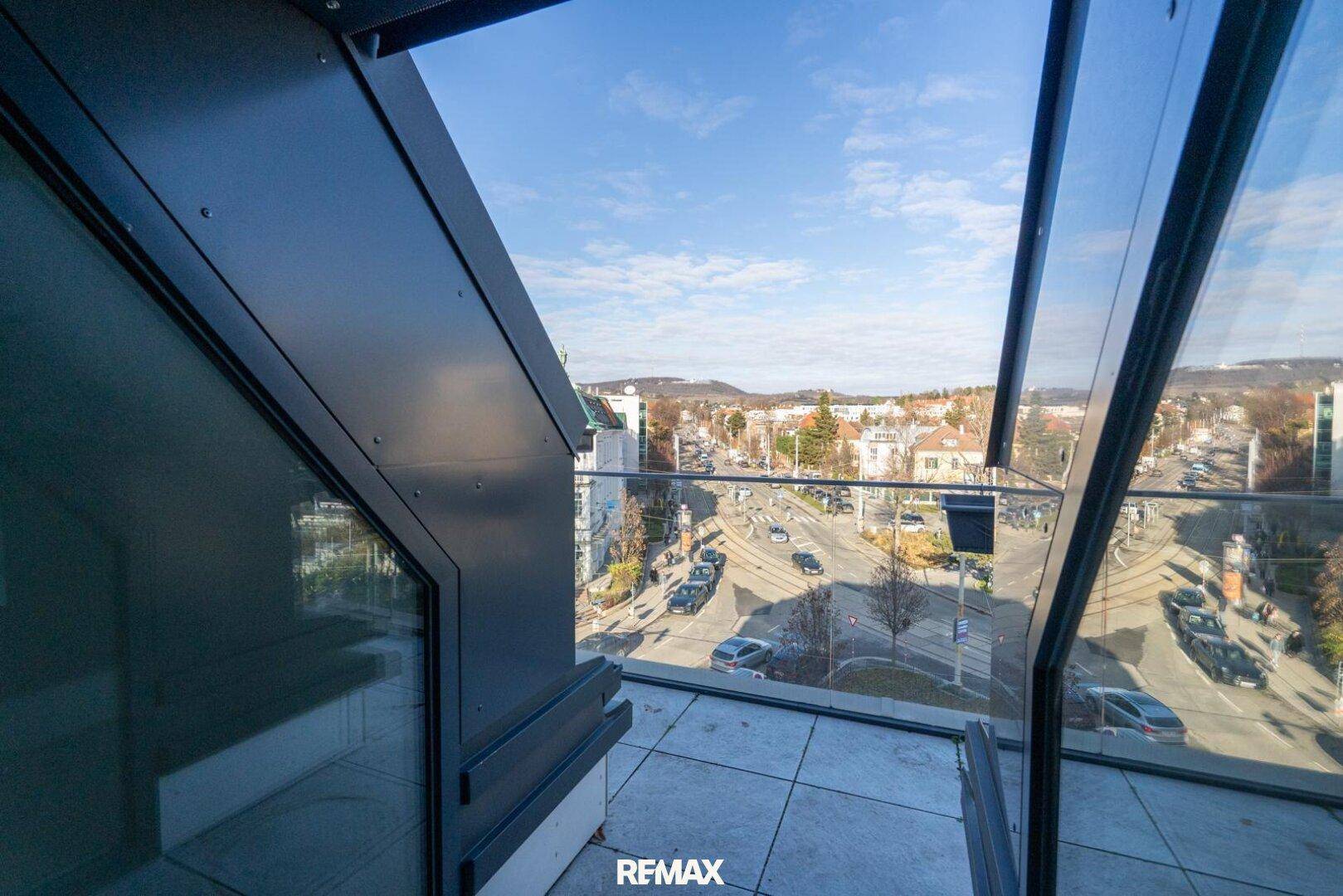 Kleiner Balkon mit Glasbrüstung und weitem Blick über die Stadt und die Umgebung.