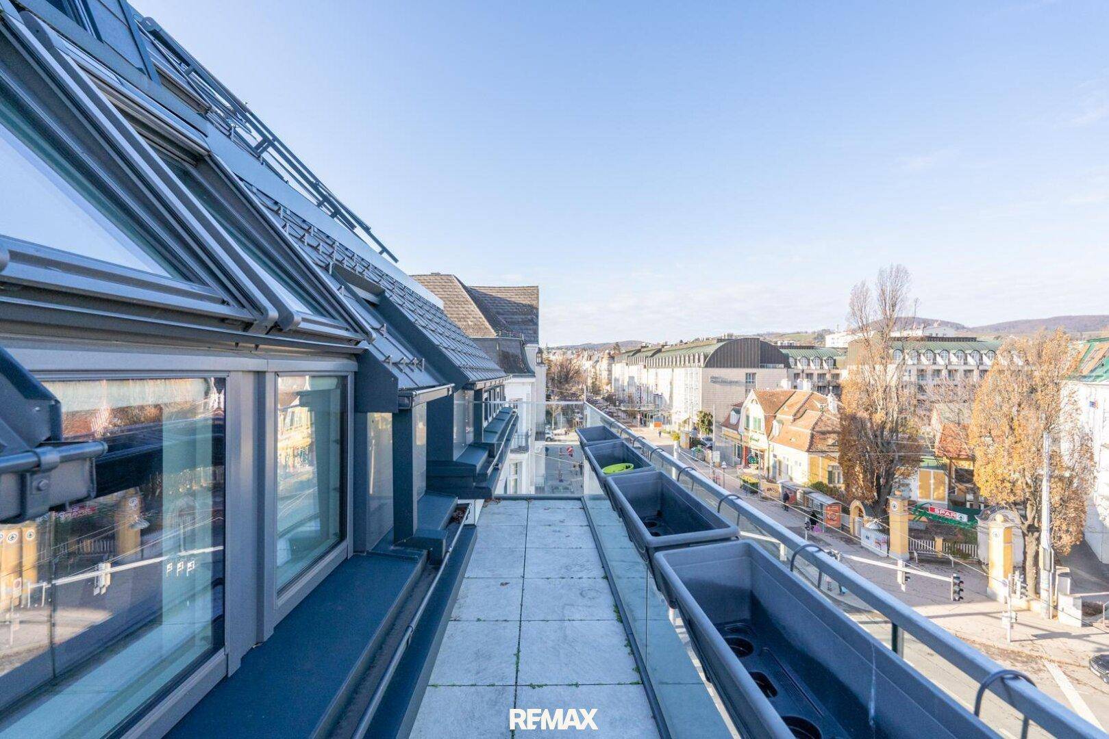 Dachbalkon mit Fliesenboden und weitem Blick über die Stadt und die grünen Hügel.