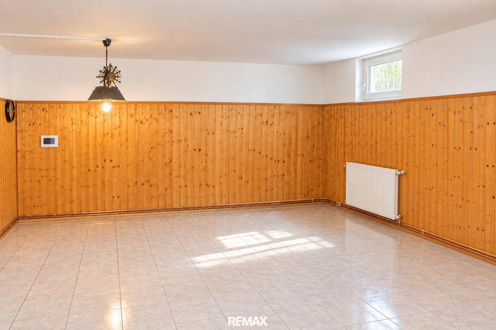 Kellerraum mit Holzvertäfelung, Fliesenboden und kleinem Fenster.