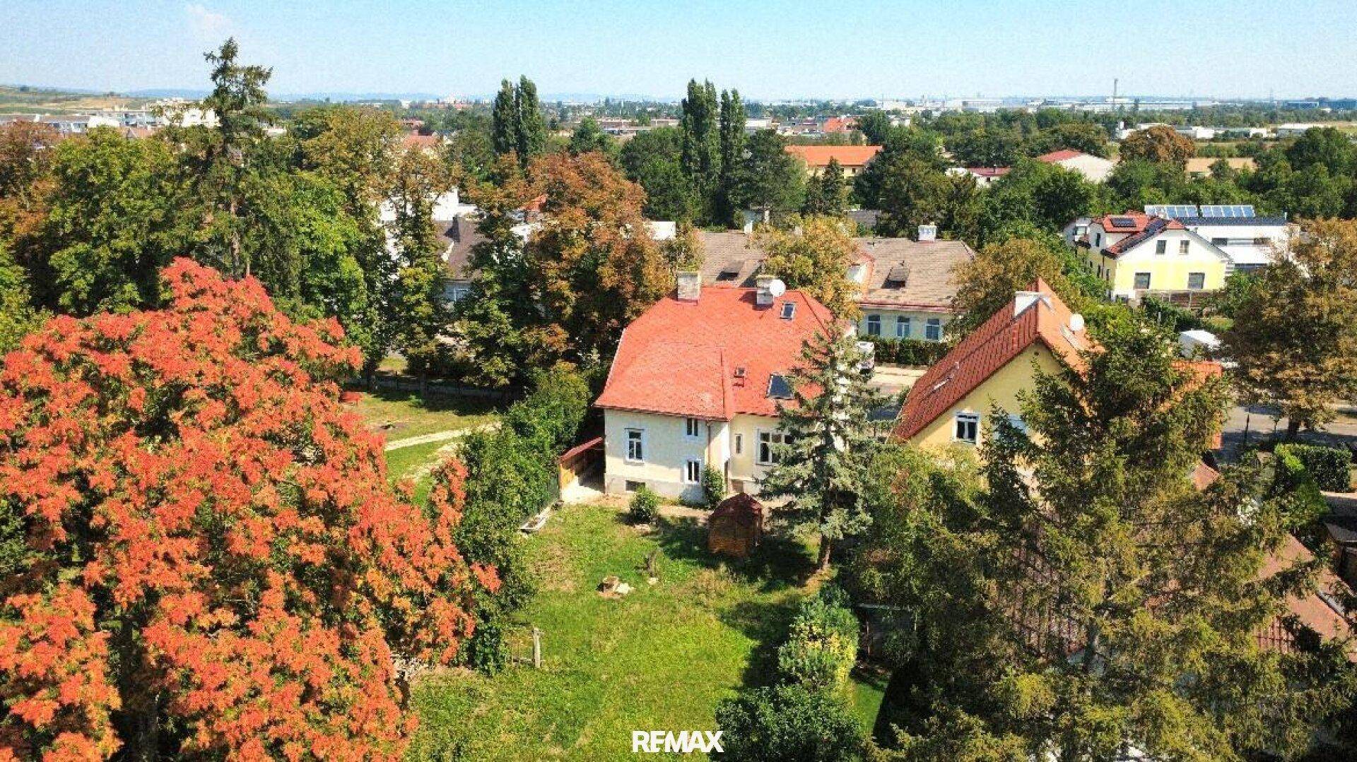 Weitläufige Luftaufnahme des Hauses und der Umgebung, mit rotem Dach und viel Grün.