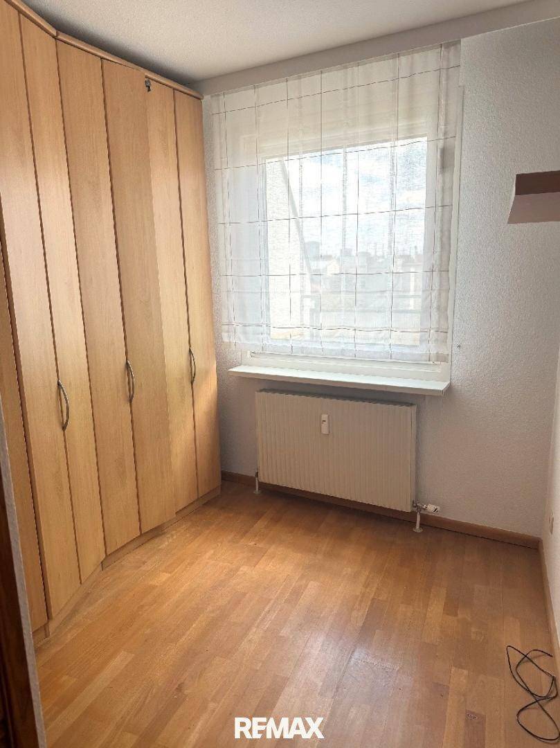 Helles Schlafzimmer mit Holzfußboden und großem Einbauschrank, gut beleuchtet durch das Fenster.