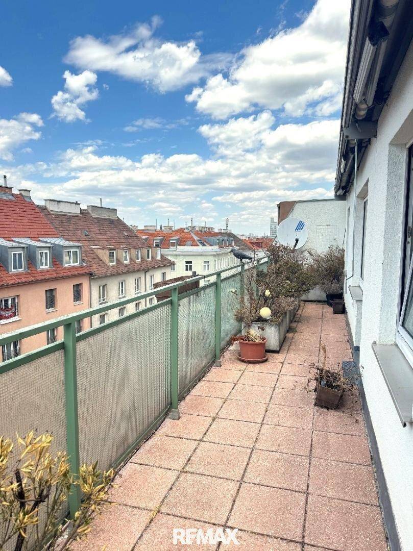 Geräumige Terrasse mit Fliesenboden, grüner Brüstung und weitem Blick über die Dächer der Stadt.