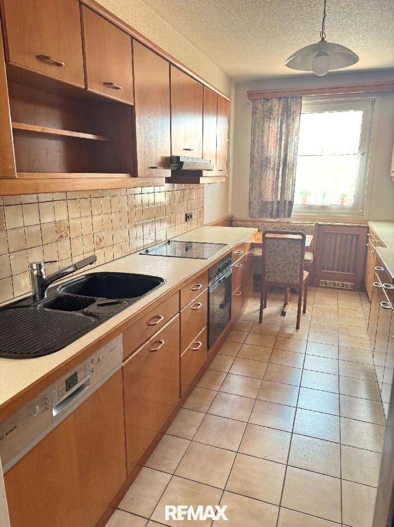 Traditionelle Küche mit Holzschränken, Fliesenboden und integrierten Geräten sowie Essbereich.
