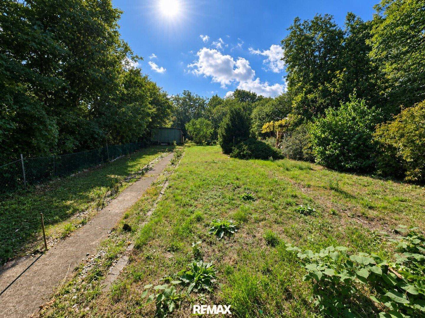 Weitläufiger Garten mit viel Grün, Bäumen und einem sonnigen Himmel.