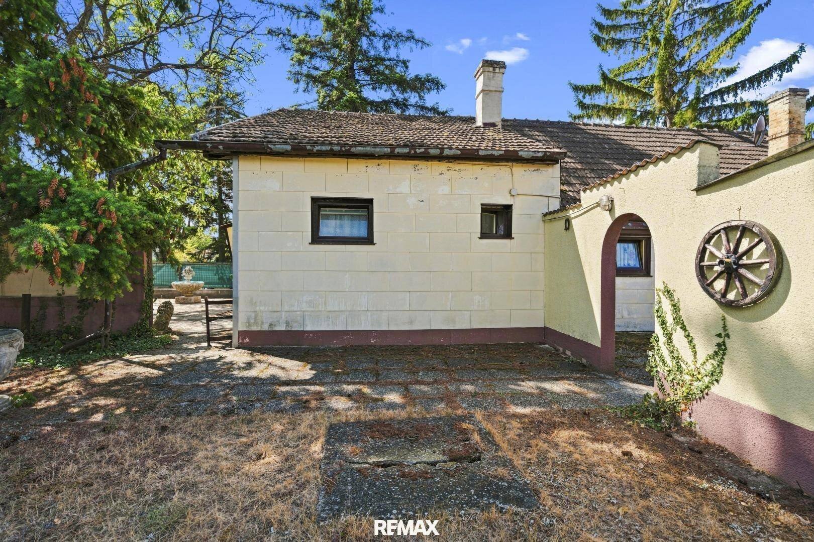 Rückansicht des Hauses mit gepflastertem Bereich und einem Nebengebäude.