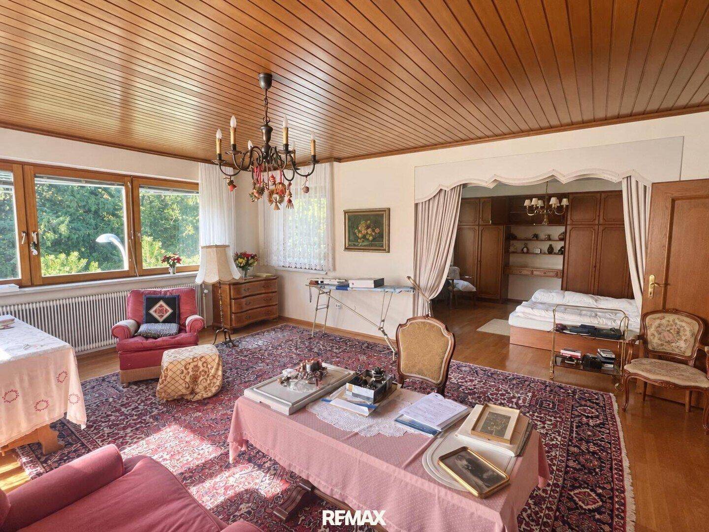 Gemütliches Wohnzimmer mit traditionellen Möbeln, Holzbalkendecke und großem Teppich.
