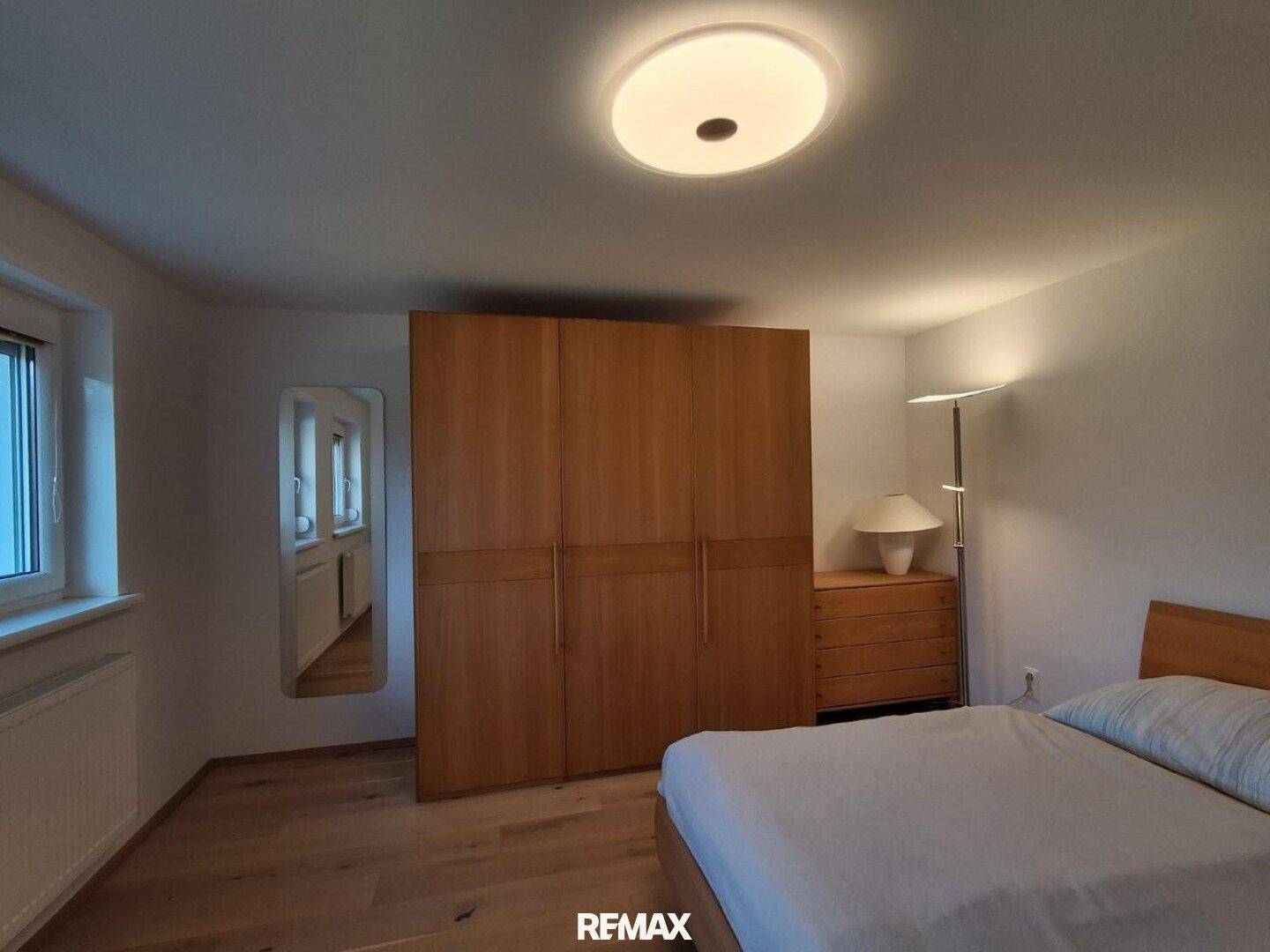 Geräumiges Schlafzimmer mit Holzboden, großem Kleiderschrank und Fenster für natürliches Licht.