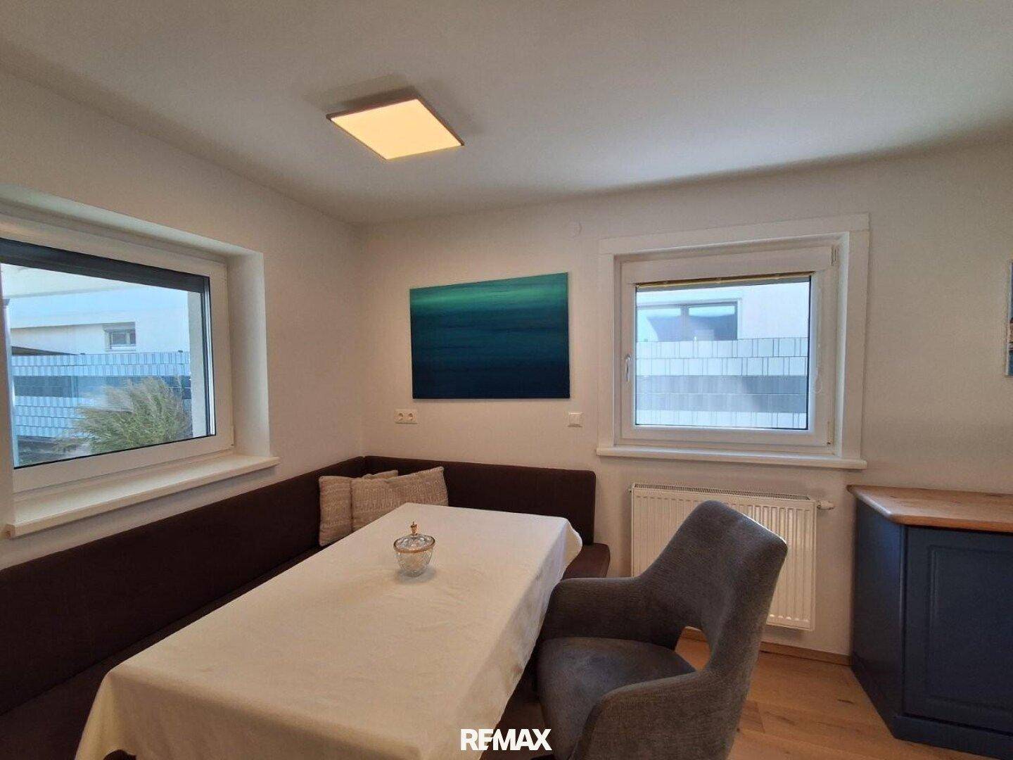 Heller Essbereich mit Eckbank, Holztisch und Blick nach draußen durch große Fenster.