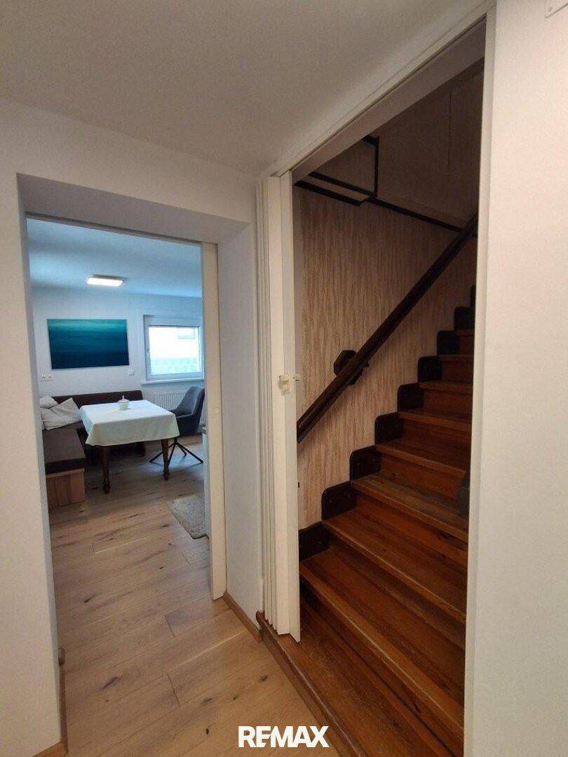 Heller Flur mit Holztreppe, die in die oberen Etagen führt, und Zugang zu weiteren Räumen.