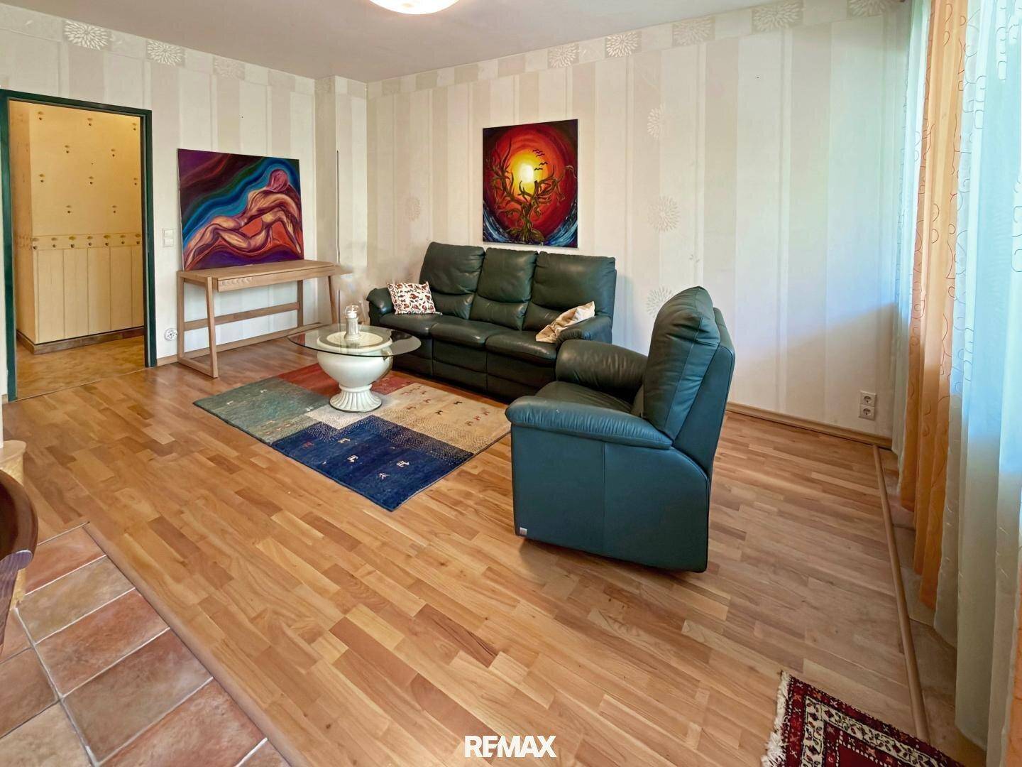 Gemütliches Wohnzimmer mit Holzfußboden, bequemen Ledersofas und dekorativen Teppichen.