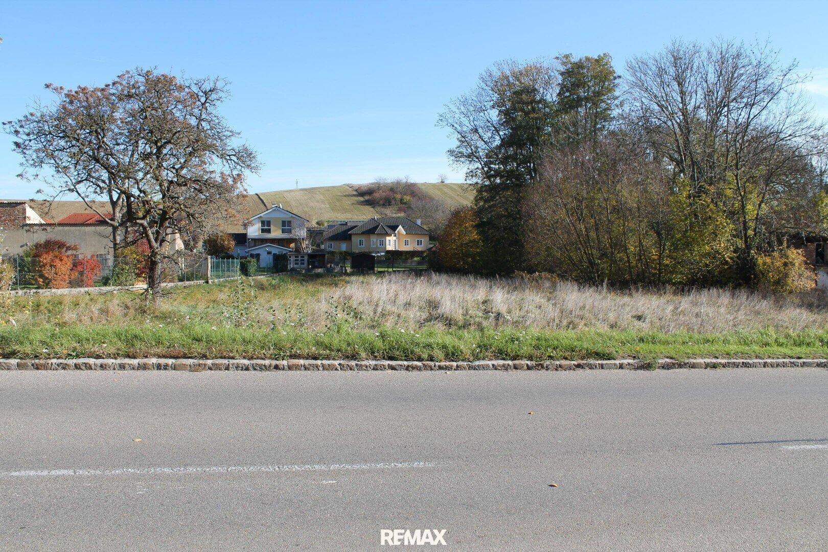 Grundstück von der Straße aus gesehen, mit Wiesenfläche und Blick auf die ländliche Umgebung.