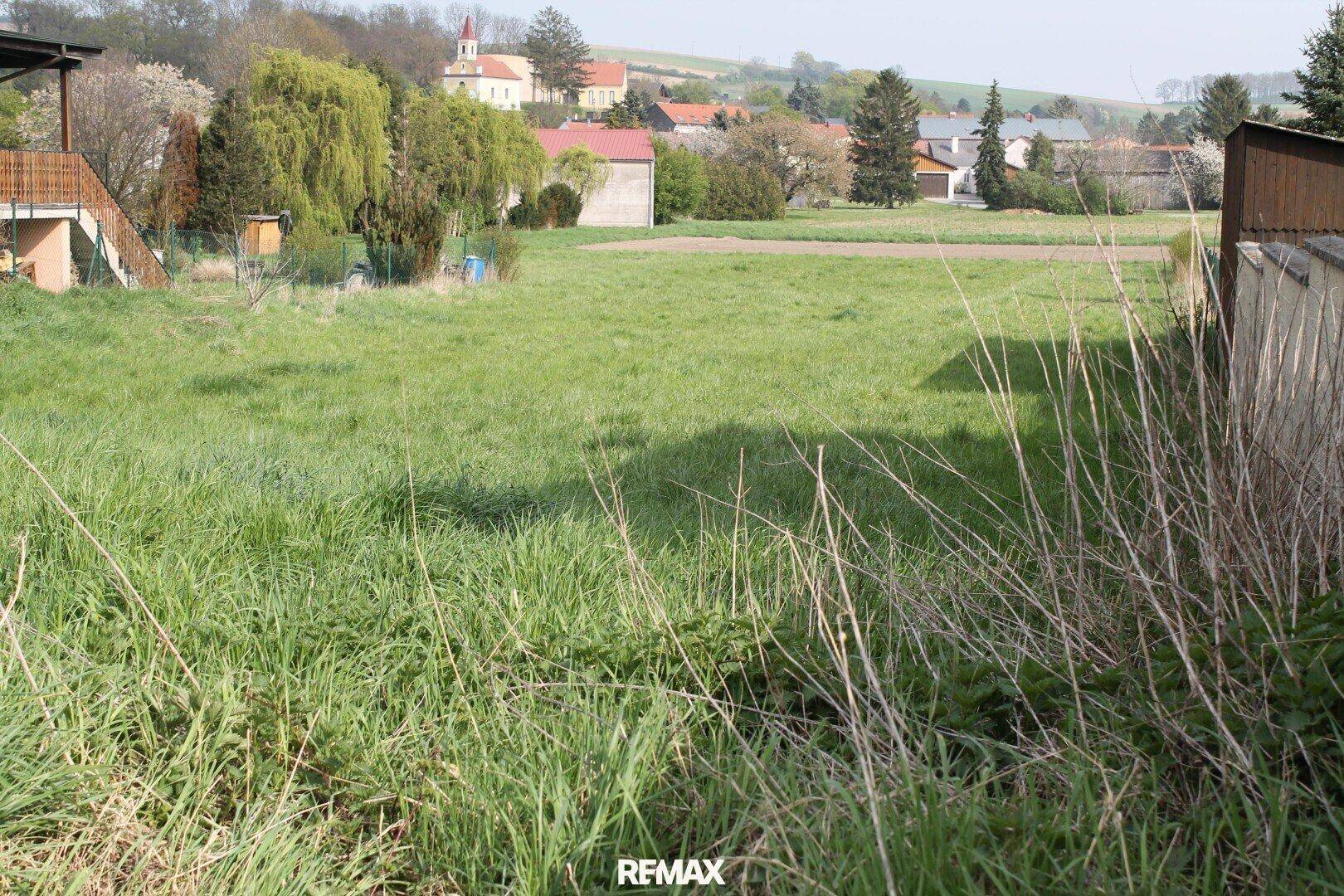 Weitläufiges grünes Grundstück mit Blick auf die umliegende ländliche Bebauung und Hügellandschaft.