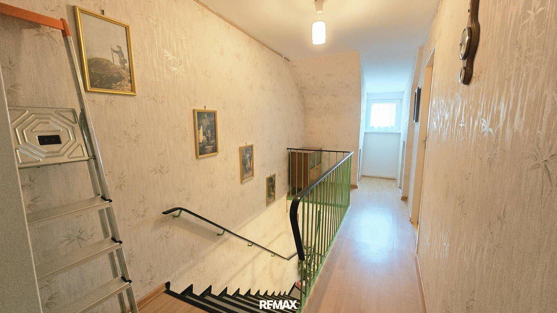 Obergeschoss-Flur mit Treppenabgang und Bildern an der Wand.