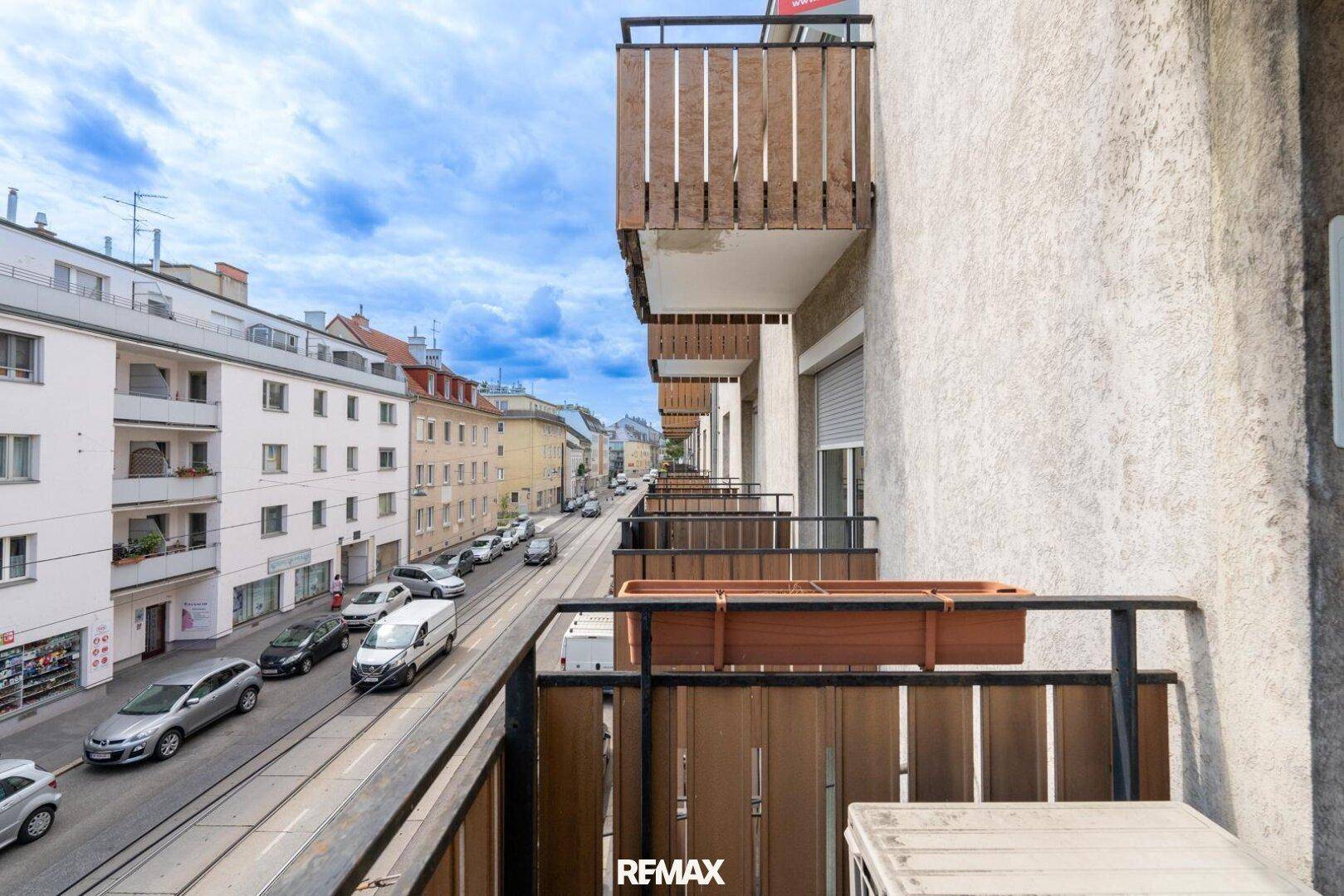 Balkon mit Holzgeländer und Blick auf die belebte Stadtstraße.